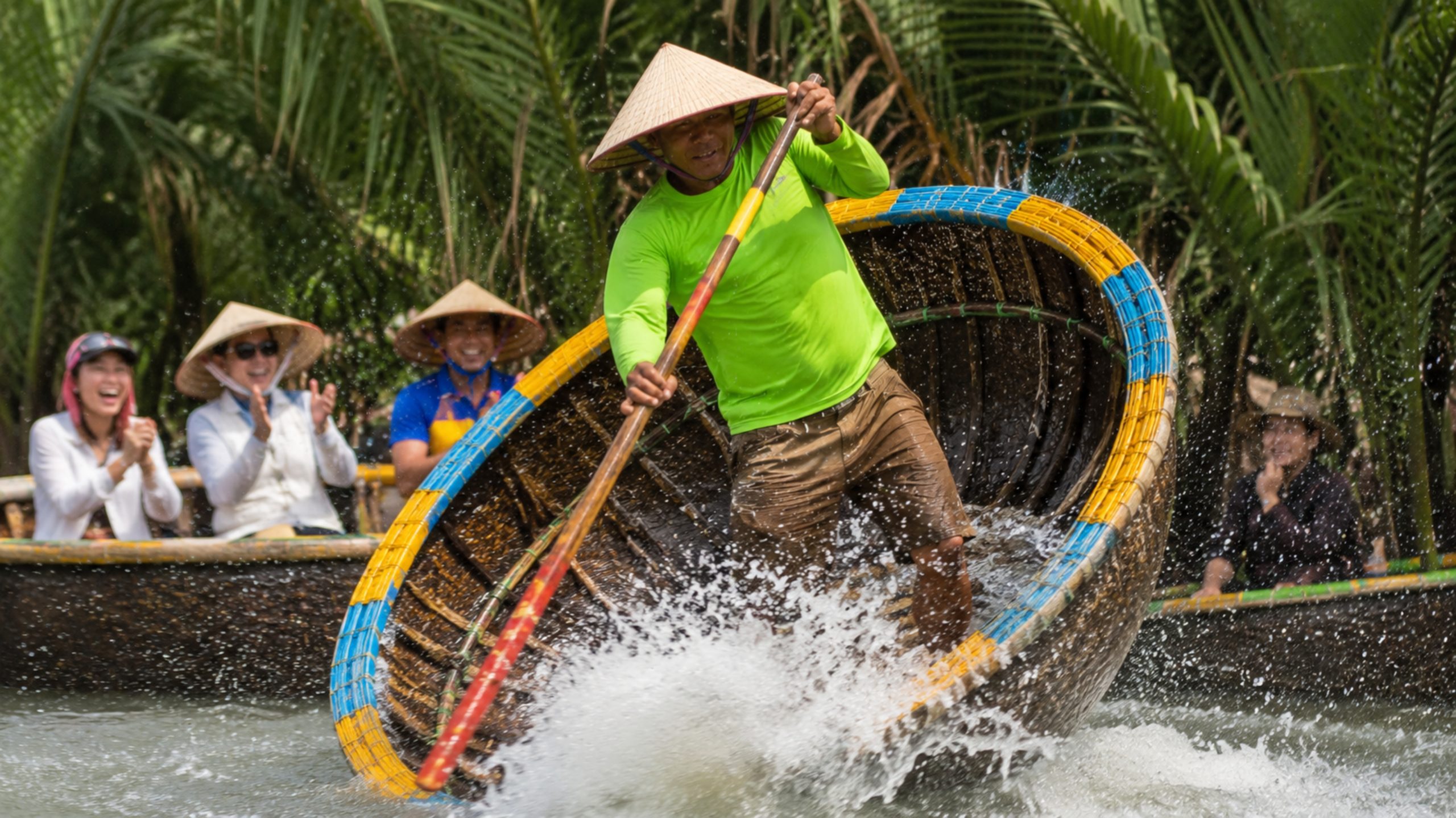 Local performer spinning a basket boat with water splashing during a Hoi An coconut village tour.