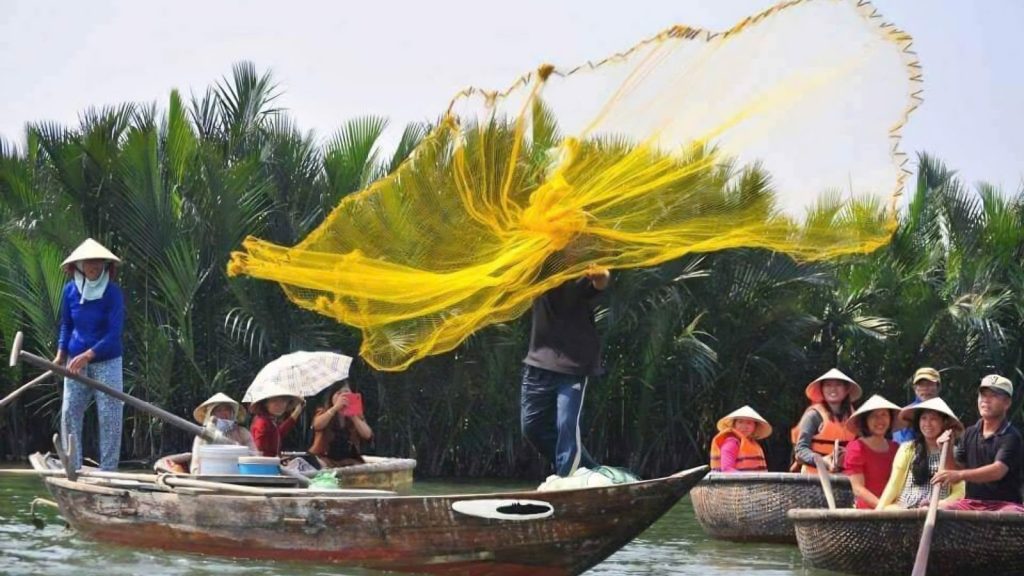 A local fisherman performs a fishing net demonstration for tourists during a basket boat tour in Cam Thanh Coconut Forest.