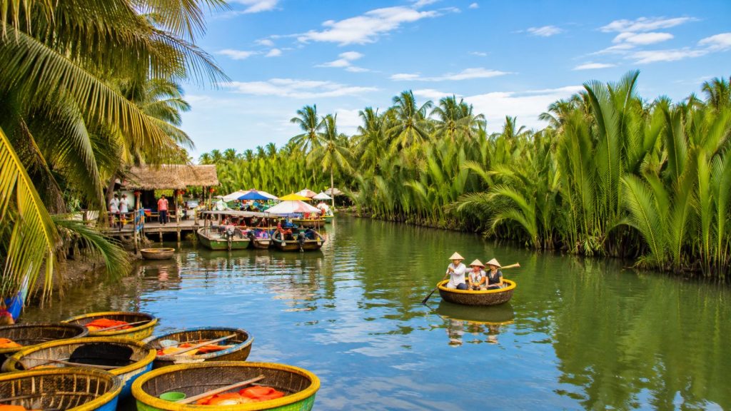 Tourists riding a basket boat on a peaceful green river surrounded by coconut palms at Hoi An Coconut Village