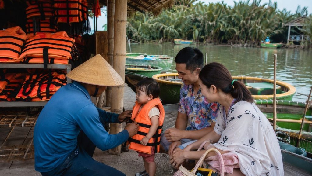 Local guide helping a toddler wear a life jacket before the boat tour.