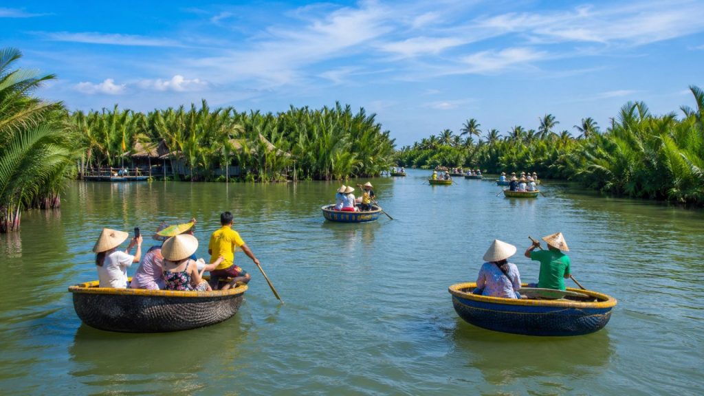 Round basket boats drifting along the calm river surrounded by coconut palms in Hoi An.