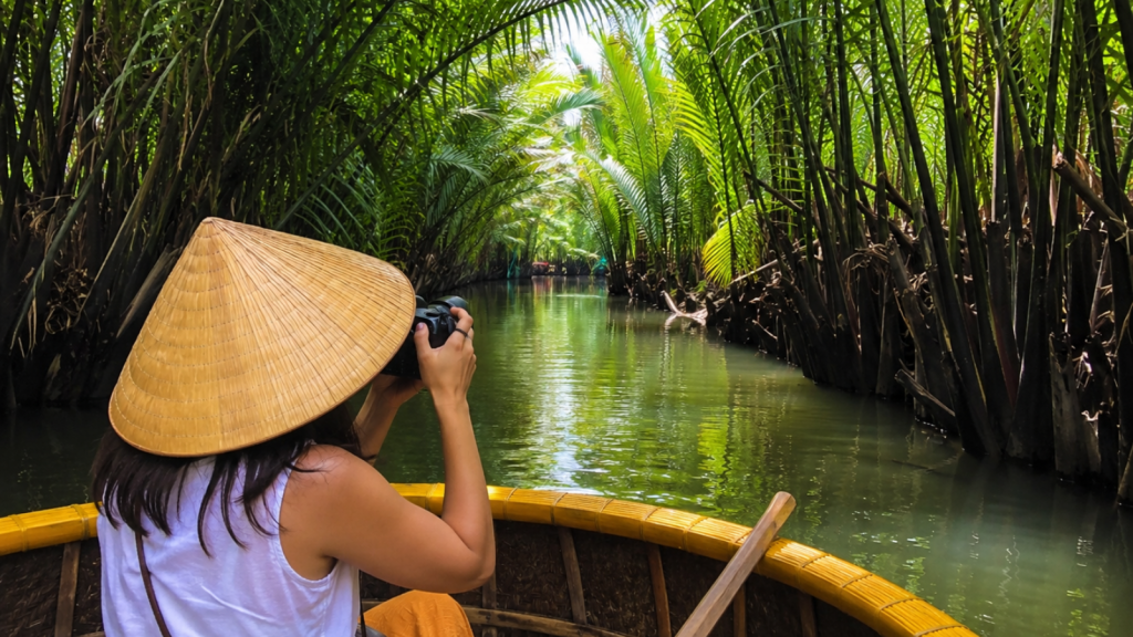 Traveler taking photos during a Bay Mau Coconut Forest boat tour.