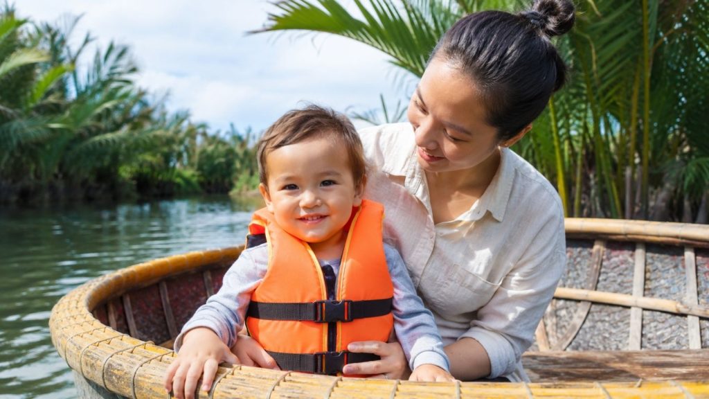 Smiling toddler sitting safely with mother in a Hoi An basket boat.