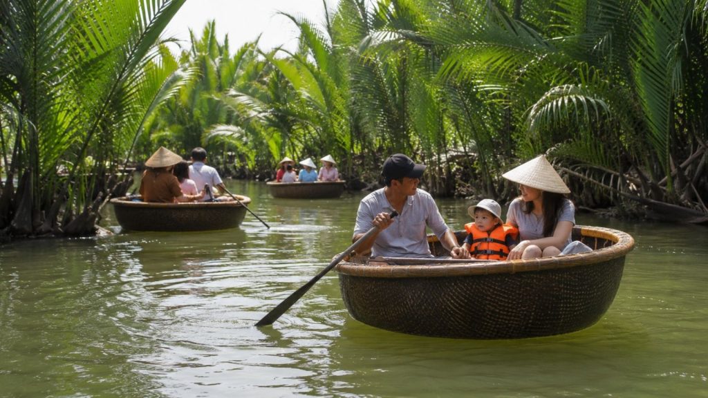 Family with toddler riding a basket boat through calm coconut forest waters.