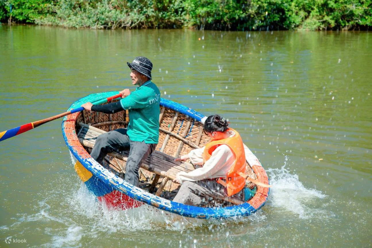Two passengers safely seated inside a traditional bamboo basket boat demonstrating the maximum weight capacity on Hoi An river