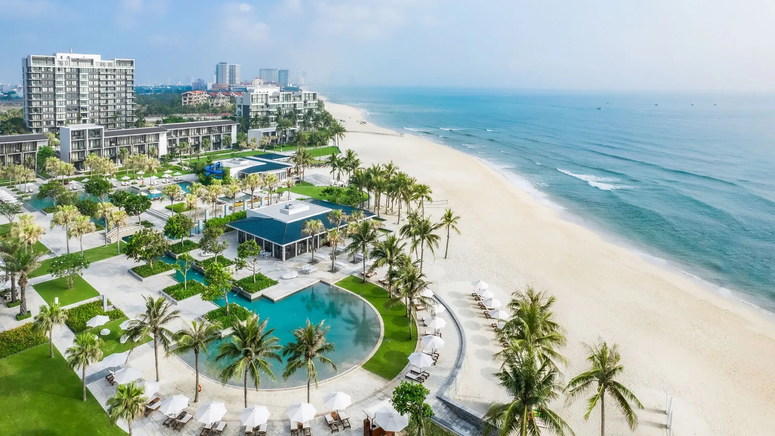 Modern beachfront resort hotels lining the white sand My Khe beach in Da Nang city with contemporary Vietnam skyline