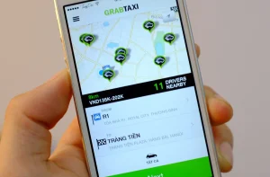 Tourist booking a Grab car on smartphone app for the Da Nang to Hoi An route showing transparent fare estimate in Vietnamese Dong