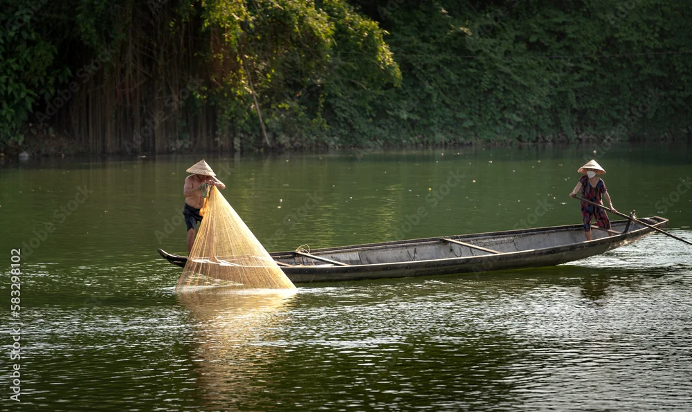 Hoi An Coconut Forest Crab Fishing & Traditional Net Casting Guide 2 Vietnamese fisherman performing traditional circular cast net throw over the calm river waters in Hoi An coconut forest